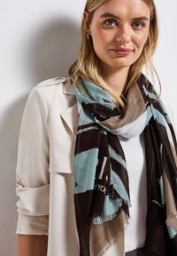 Multifarvet tørklæde med abstrakte mønstre i aqua, brun og beige. Blødt stof med flagrende kanter, draperet omkring bærerens hals.