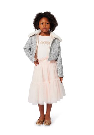 Kinderoutfit bestaande uit een zilveren sequinjas met een nepbontkraag, een roze tule rok en gouden ballet flats. De tekst op het shirt luidt "GLITTER IS MIJN TEKEN."