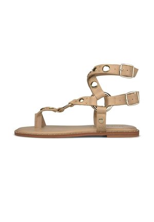 Flache Sandale aus hellbraunem Leder mit Knöchelriemen, goldfarbenen runden Nieten und seitlichen Schnallen auf einer hellbraunen Sohle.