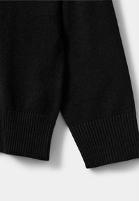 Manica di maglione nero a maglia con orlo a costine e texture morbida, caratterizzata da un design senza soluzione di continuità e colore uniforme.