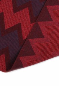 Red and dark blue patterned fabric featuring a zigzag design with a textured finish, showcasing vertical and horizontal lines.