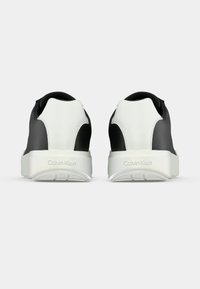 Ασπρόμαυρα αθλητικά παπούτσια με λείο δερμάτινο επάνω μέρος, ανυψωμένη φτέρνα και υφή από καουτσούκ στη σόλα. Φέρουν το λογότυπο Calvin Klein στη φτέρνα.
