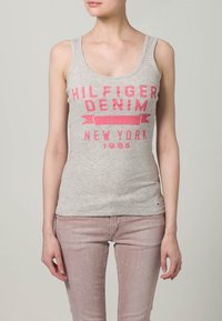 Grå bomullstanktop med fet rosa tryck "HILFIGER DENIM NEW YORK 1985". Enkel design; figurnära passform; inga utsmyckningar.