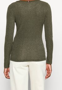 Olijfgroene lange mouw ribtop met metallic glans, voorzien van een ronde halslijn en subtiele stikdetails langs de zoom.