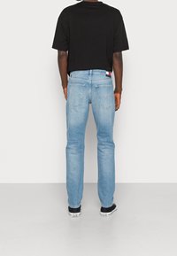 Modré denimové džíny s rovnými nohavicemi, standardním pětipocketovým stylem a značkovou zadní nášivkou. Vybavené černým tričkem s krátkým rukávem.