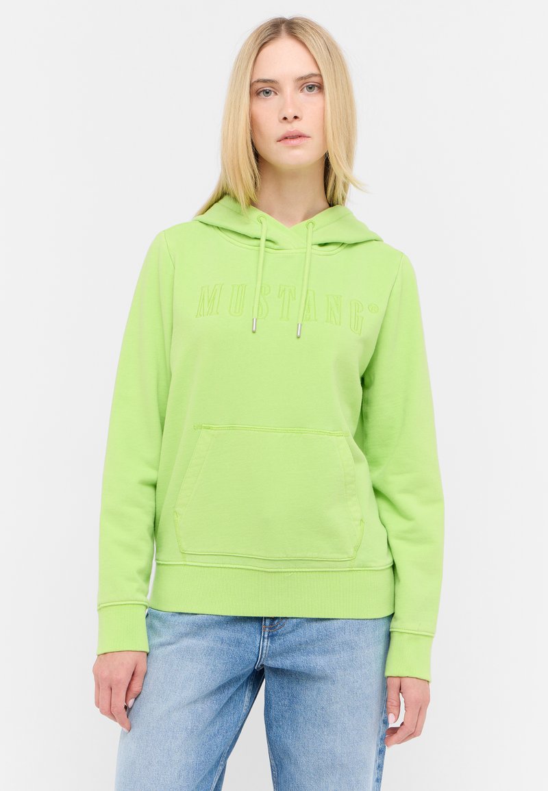 Sudadera de algodón verde con bolsillo tipo canguro y capucha con cordón. Presenta el logo "MUSTANG" en un diseño ligeramente levantado. Corte relajado.