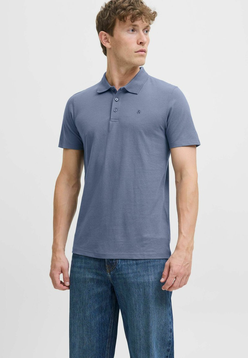 Polo à manches courtes en coton bleu clair uni, avec un col à trois boutons et un petit logo brodé sur la poitrine.