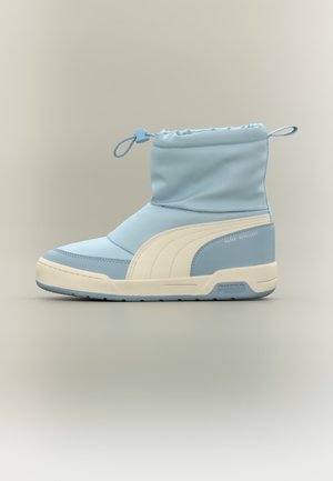 Botte montante Puma bleu clair et blanche avec fermeture à cordon et matériau déperlant sur fond neutre.