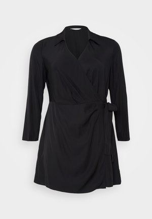 Črna obleka s dolgimi rokavi, ovratnikom in detajlom z vezanjem v pasu. Izdelana iz mehke in gladke tkanine z drapirano silhueto.