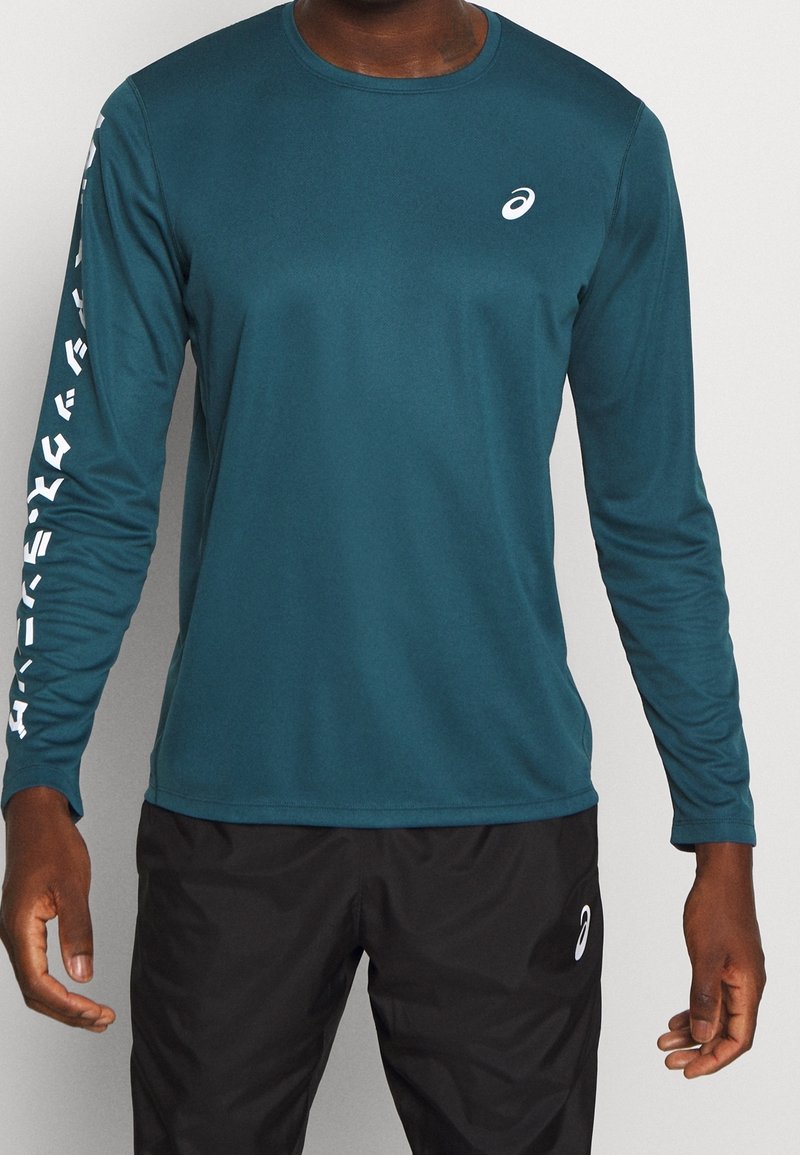 Tealfarbendes, langärmliges Sportshirt aus atmungsaktivem Material. Hat einen runden Ausschnitt und weiße Markenlogo auf dem linken Ärmel.