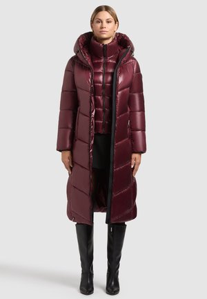 Lange bordeaux rode pufferjas met een hoge kraag en capuchon. Kenmerkt zich door een gewatteerd ontwerp en een contrasterende zwarte rits. Gemonteerd over een kortere puffer.
