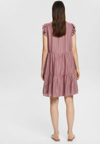Robe rose poussiéreux avec des manches courtes ruffle, une jupe à volants et une coupe décontractée. Texture lisse avec des rayures verticales pour un détail supplémentaire.