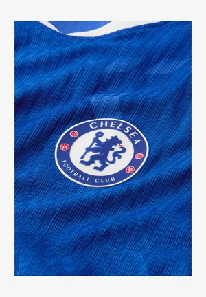 Sininen Chelsea Football Clubin pelipaita, jossa on seuran vaakuna, jossa leijona pitää sauvaa ja punaisia kukka- ja jalkapallokuvioita.