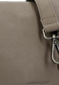 Borsa in pelle grigia con superficie testurizzata, tracolla removibile e accessori in metallo con clip per la chiusura. Il logo del marchio è impresso.
