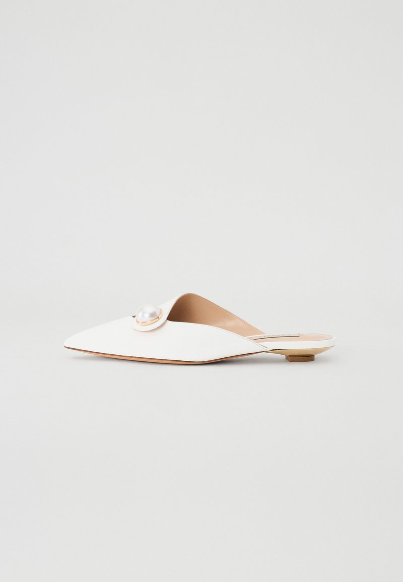 Mule brancas planas com biqueira pontuda, apresentando um detalhe circular de pérola com ferragem dourada. Material suave com um design minimalista.