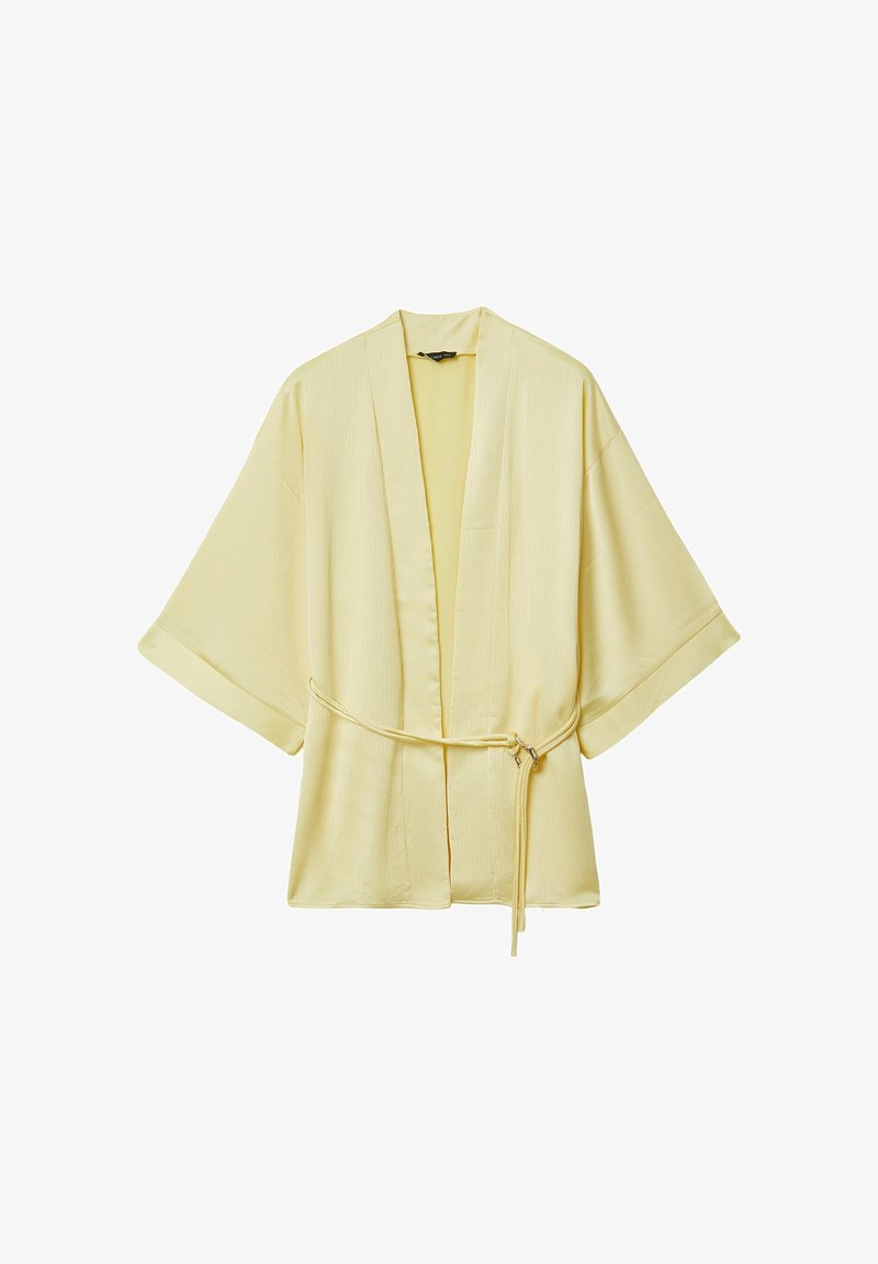 Giacca stile kimono di colore giallo chiaro con maniche ampie e una sottile cintura annodata in vita, mostrata su uno sfondo bianco.