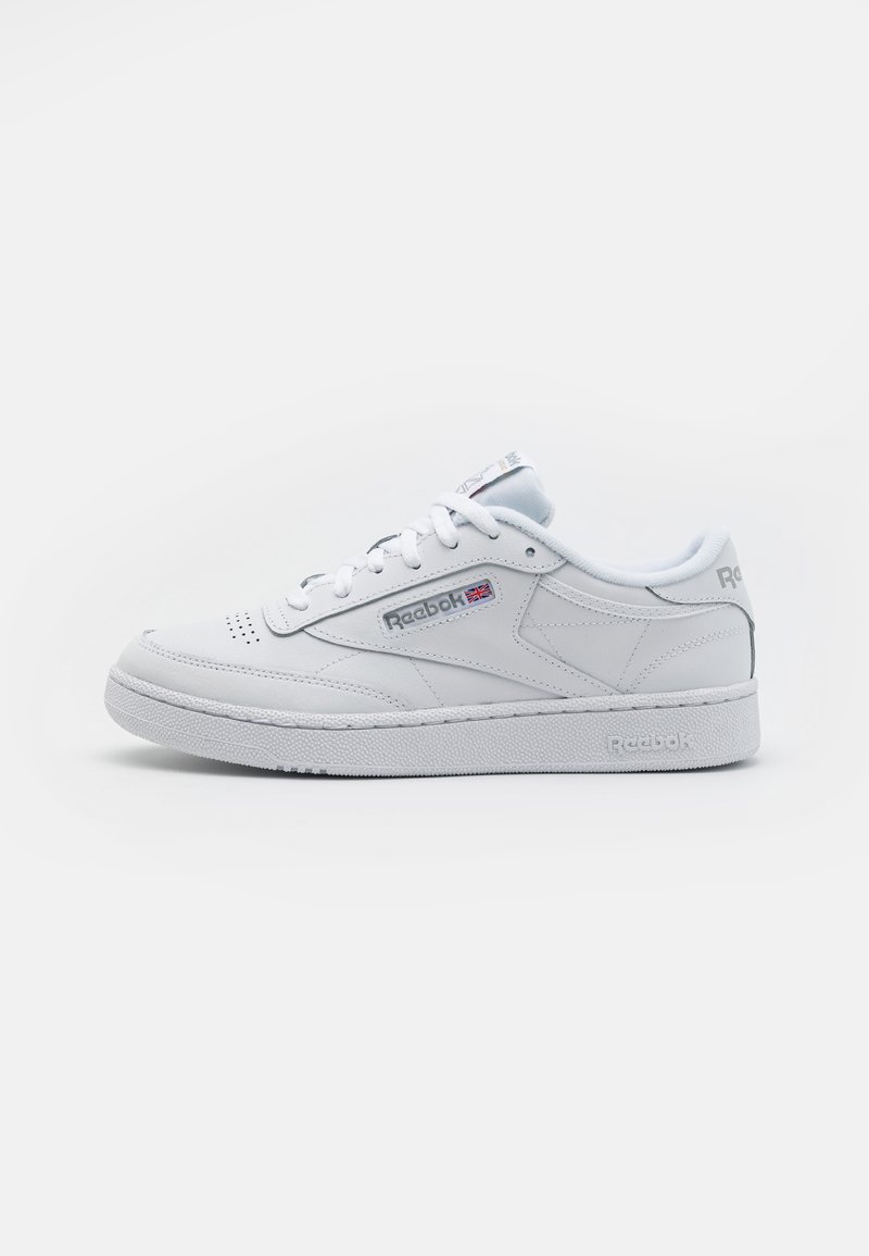 White leather sneaker with a smooth texture, rounded toe, lace-up front, and logo accents. Rubber sole for grip and durability.