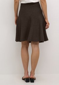 Jupe évasée marron en tissu doux et texturé. Dotée d'une taille haute, elle tombe au-dessus du genou avec un ourlet net. Pas de motifs ou d'accents visibles.