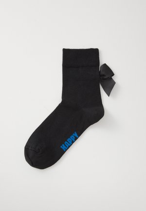 Black sock made from soft fabric, featuring a ribbed cuff and a black ribbon bow. The word "HAPPY" is printed in blue on the side.