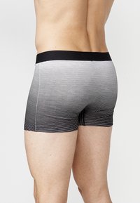 Herren-Boxershorts mit einem schwarzen elastischen Bund. Der Stoff weist horizontale Streifen auf, die von Grau zu Schwarz übergehen. Glatte Textur.