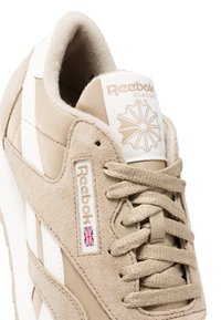 Béžové tenisky Reebok Classic s rúžovým a sieťovaným materiálom, bielymi akcentmi, okrúhlymi šnúrkami a logom na jazyku a boku.