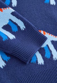 Pletený sveter v námorníckej modrej farbe s textúrovaným lemom, zdobený modrými a bielymi zvieracími motívmi a oranžovými akcentmi.