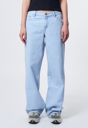Light blue, wide-leg jeans feature a classic five-pocket design, button closure, and a soft denim texture. Worn with gray sneakers.