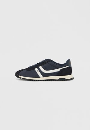 Baskets bleu marine avec des bandes blanches sur le côté, un bout noir, le logo "BOSS" sur le côté et une semelle beige et noire striée.