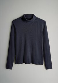 Zwarte turtleneck shirt met lange mouwen en een ribbelstructuur, plat weergegeven tegen een effen lichtgrijze achtergrond.