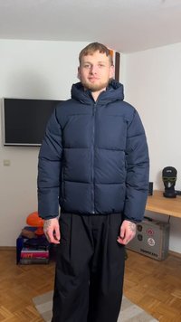 Tamsiai mėlyna pūkinė striukė su gaubtu, priekyje užtrauktuku ir matomomis siūlėmis. Dėvima su juodomis kelnėmis, uždarose patalpose.