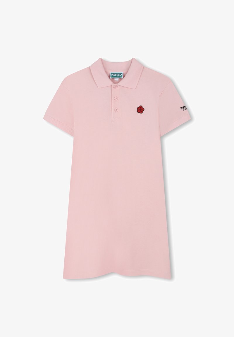 Polo rose avec un col classique, une patte de boutonnage à quatre boutons, des manches courtes et un logo de fleur rouge brodé sur la poitrine. Texture lisse.