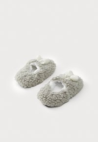 Pantofole grigie pelose con un esterno testurizzato, design aperto e decorazioni con pompon bianchi. Fodera morbida per comfort e calore.