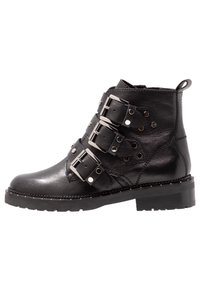 Černá kožená kotníková bota se třemi stříbrnými přezkami, kulatými kovovými akcenty, texturovaným povrchem a robustní gumovou podrážkou.