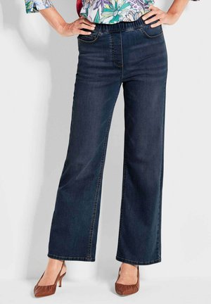 Donkerblauwe wijde jeans van denim, met een rekbare tailleband en twee voorzakken. Gecombineerd met bruine hakken.