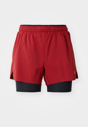 Shorts de sport rouges avec doublure intérieure noire, taille élastique, fentes latérales et détail de logo. Matériel léger et respirant conçu pour le mouvement.