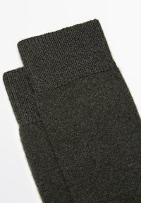Dunkelgrüne, gerippte Stricksocken mit einer weichen, strukturierten Oberfläche und einem Kontrast am Bündchen. Entworfen für Komfort und Wärme.