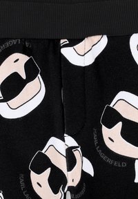 Tessuto nero con volti in stile cartone animato ripetuti e occhiali da sole. Vita elasticizzata e stampa con il testo "KARL LAGERFELD". Texture morbida.
