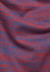 Tissu tissé texturé dans un mélange de tons rouges et bleus, présentant un motif subtil de rayures à travers la surface.