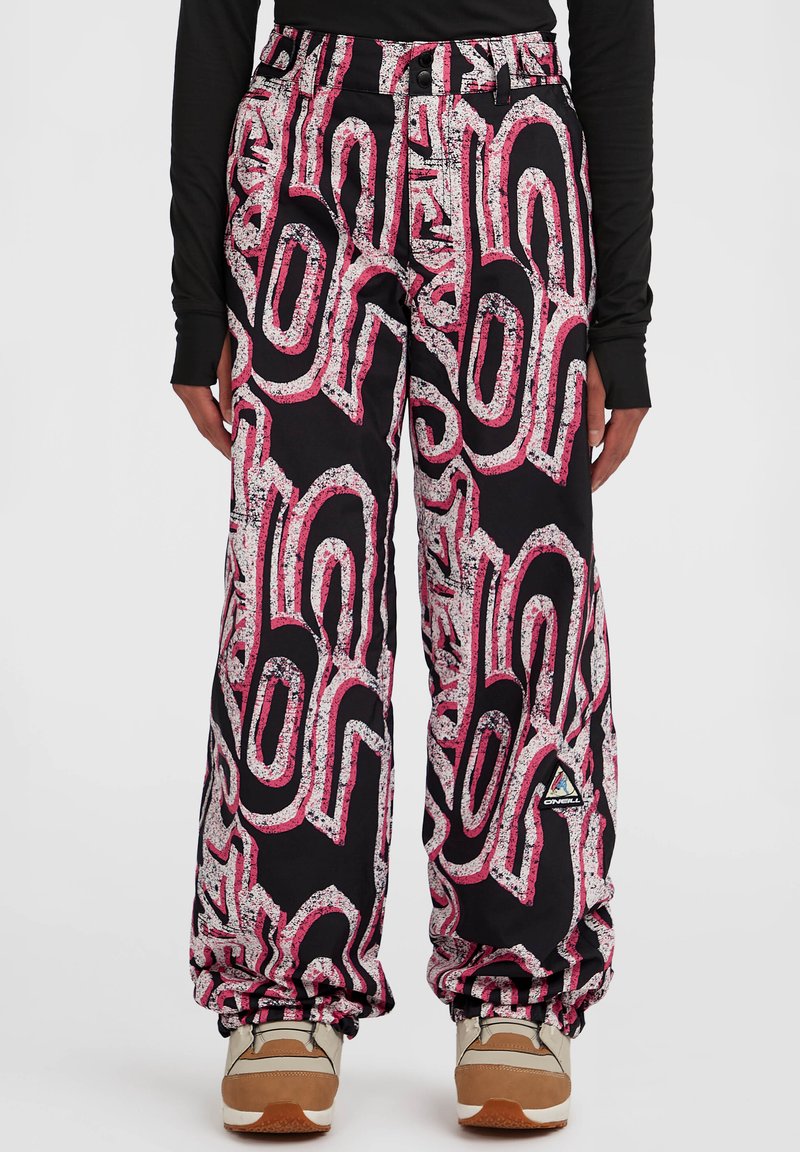 Zwart geblokte broek met gedurfde roze en witte abstracte ontwerpen, met een relaxte pasvorm en elastische manchetten, gecombineerd met beige schoenen.