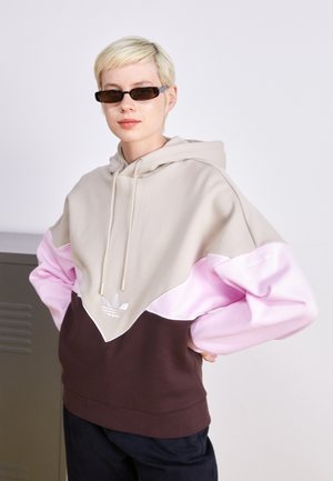 Sweatshirt à capuche présentant un design en blocs de couleurs beige, rose et marron. Fabriqué en matériau doux avec un logo avant et des détails de cordon de serrage.