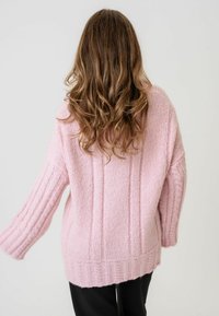 Rozā adīta džemperis ar ribotu tekstūru, brīvs piegriezums un izteikti pleci. Biezas šuvju detaļas gar piedurknēm un apakšmalu.