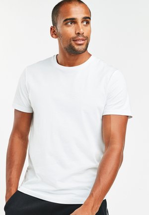 Valkoinen crew-neck t-paita, joka on valmistettu sileästä puuvillakankaasta. T-paidassa on lyhyet hihat ja slim fit -leikkaus ilman näkyviä kuvioita tai yksityiskohtia.