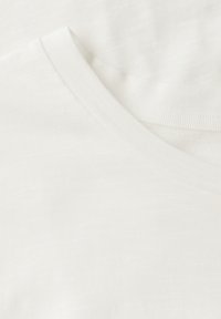 Hvid bomulds t-shirt med et blødt, struktureret stof, der har en v-hals og en synlig ribbet krave.