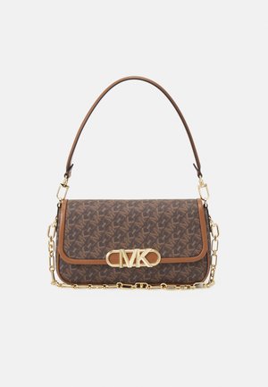 Bruine monogram-schoudertas met gouden MK-logo aan de voorkant, leren afwerking en gouden ketting en leren riem op een witte achtergrond.