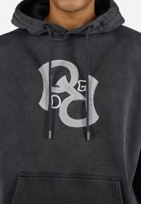 Dark gray hoodie made of cotton, featuring a large, layered gray logo on the chest and matching drawstrings with metal tips.