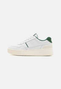White leather sneaker with green accents. Features a textured sole, round toe, lace-up design, and embossed logo on the side.