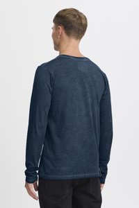 Langärmliges Rundhals-T-Shirt in dunklem Marineblau, hergestellt aus weichem, strukturiertem Stoff. Verfügt über ein dezentes Logo am hinteren Halsbereich und eng anliegende Ärmel.