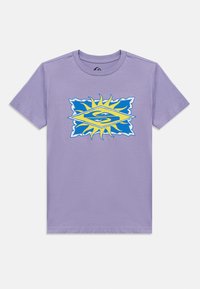 Μπλούζα με κοντά μανίκια σε λιλά χρώμα, με γραφικό σχεδιασμό ήλιου σε μπλε και κίτρινο και ένα στυλιζαρισμένο λογότυπο "S" στο κέντρο μπροστά.