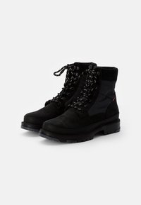 Botas de tobillo negras con un upper de ante texturizado y nylon, cordones redondos con acentos reflectantes y una suela de goma resistente.