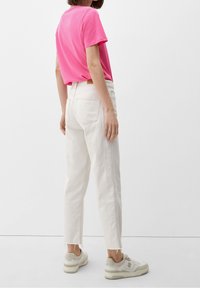 Åtsittande rosa bomullströja i kombination med off-white avkortade jeans och ljusa sneakers, med fransad fåll och bakfickor.